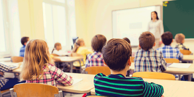 Young students sitting in a classroom with their teacher