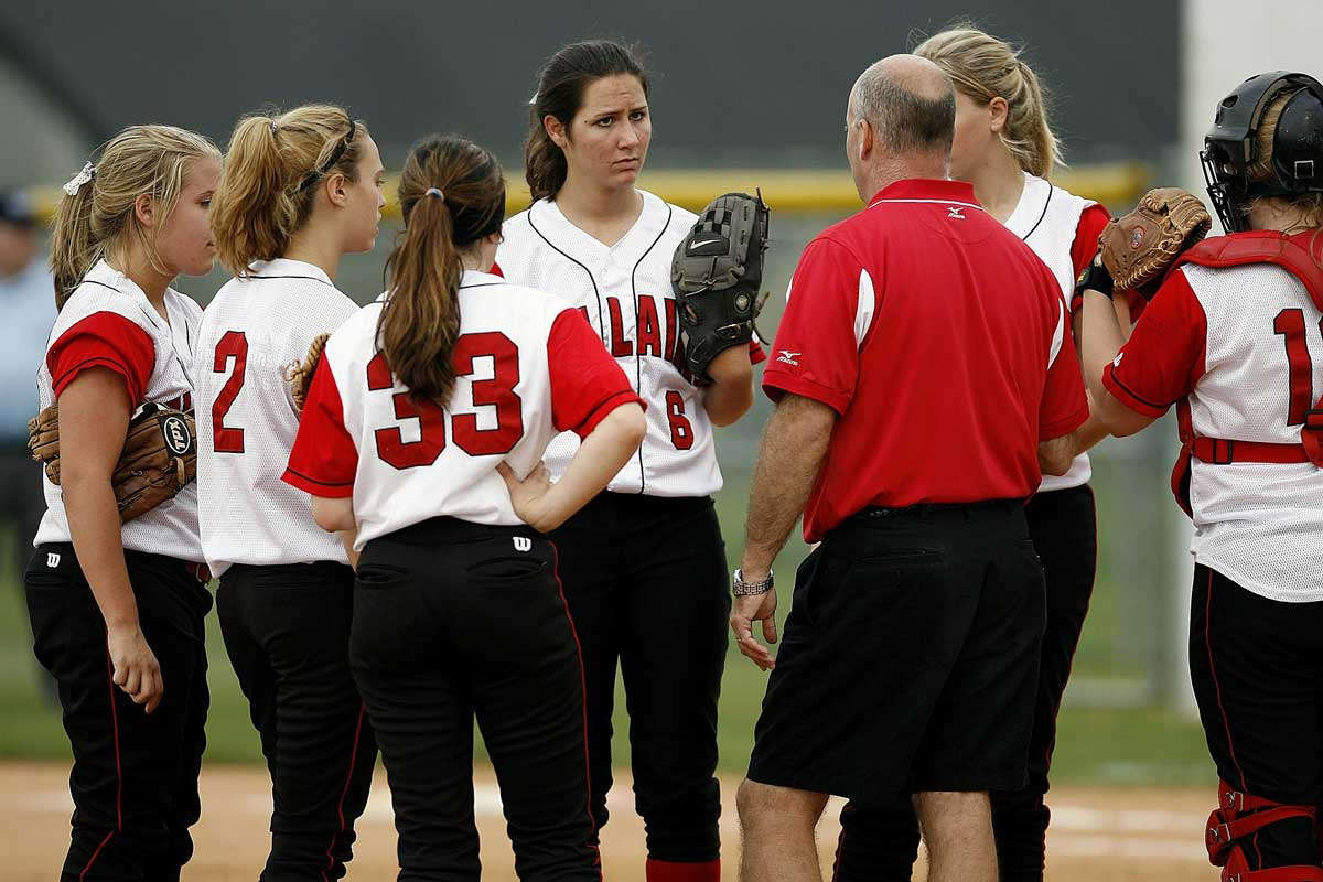 Male coach speaks to girls softball team