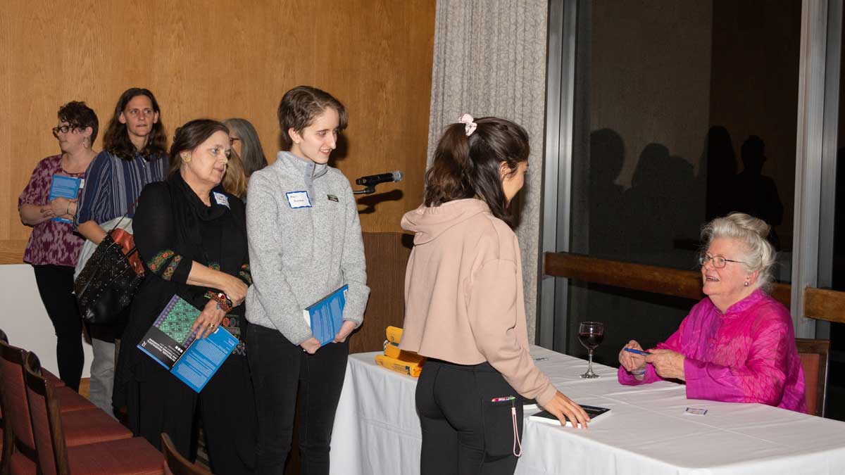 An enthusiastic, intergenerational crowd lines up to get their book signed by Dr. Peggy McIntosh.